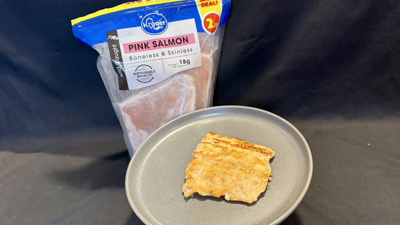 piece of cooked salmon on plate in front of package