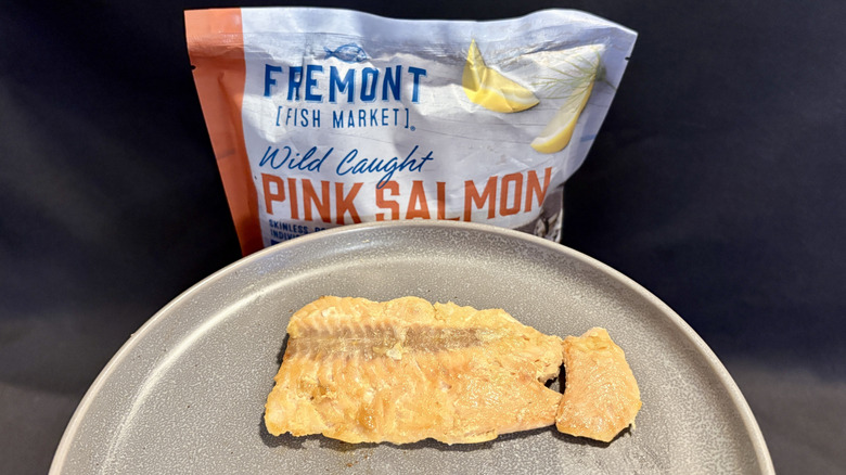 piece of cooked salmon on plate in front of package