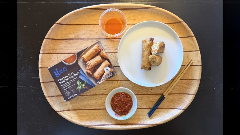 Good & Gather Frozen Chicken Thai Basil Spring Rolls on a wooden tray next to their box and a dish of sambal