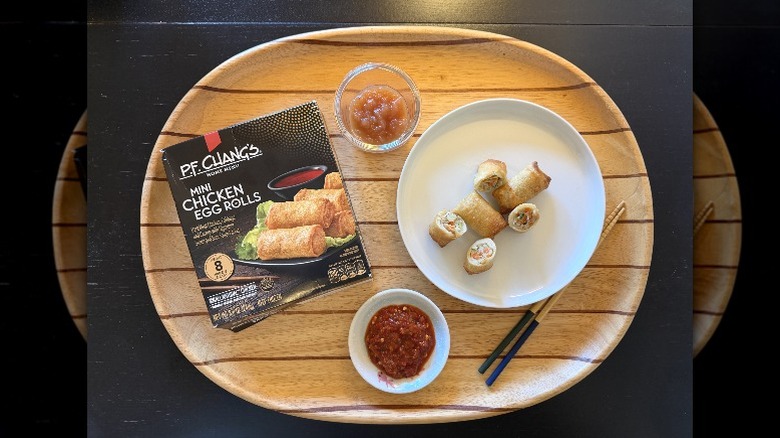 P.F. Chang's Mini Chicken Egg Rolls on a wooden tray next to their box and a dish of sambal