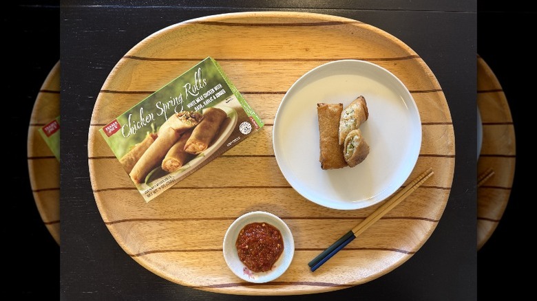 Trader Joe's Chicken Spring Rolls on a wooden tray next to their box and a dish of sambal