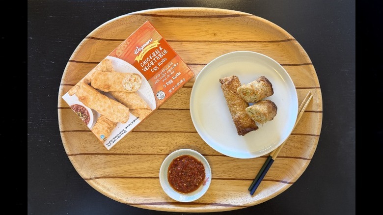 Wegmans Chicken & Vegetable Egg Rolls on a wooden tray next to their box and a dish of sambal