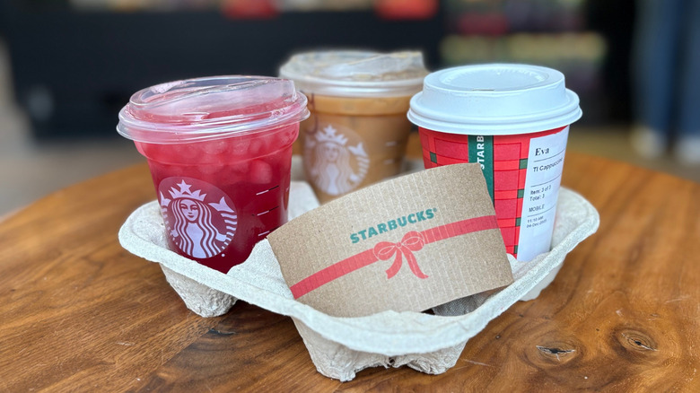 A tray of Starbucks drinks on a wood table with a blurry background