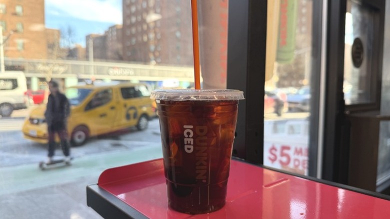 A Dunkin' Cold Brew Coffee in front of a window