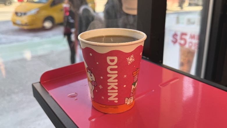 A Dunkin' Hot Coffee in front of a window