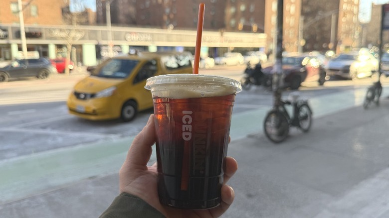 A hand holding a Dunkin' Raspberry Black Iced Tea
