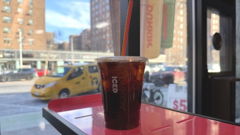 A Dunkin' Sugar-Free Vanilla Iced Coffee in front of a window