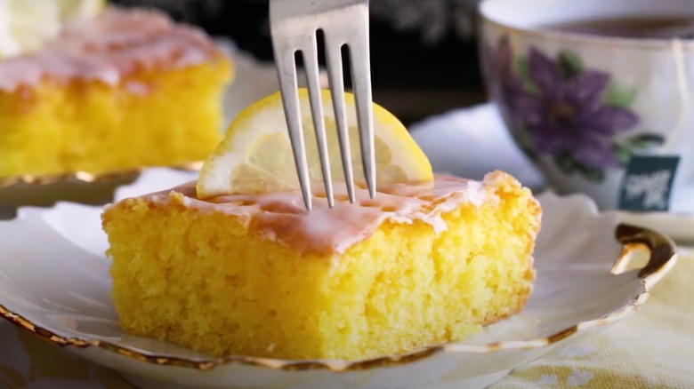 A fork hovers over a lemon jell-O cake