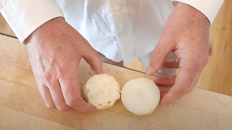 An overhead view of a man's hands making an onion sandwich