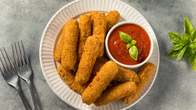 Mozzarella sticks on a dish with cup of sauce