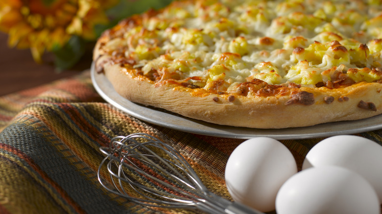 Breakfast pizza with eggs and whisk