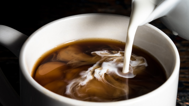 Pouring creamer into cup of coffee