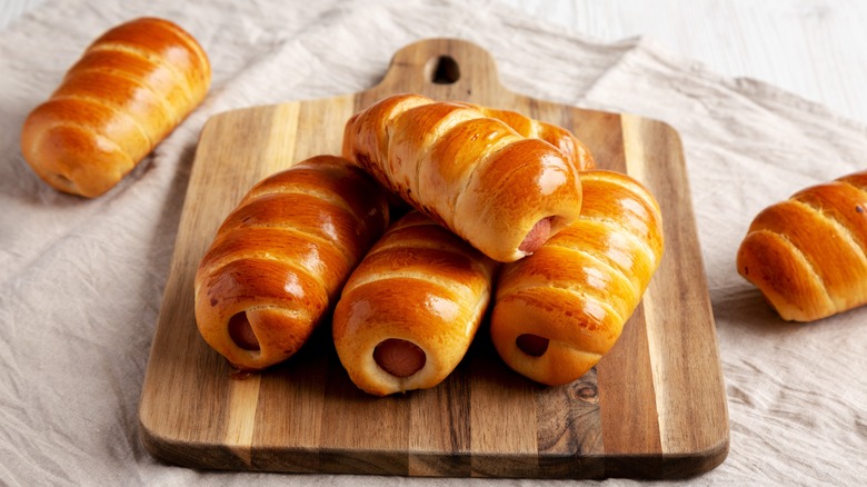 Golden baked pigs in a blanket on a cutting board
