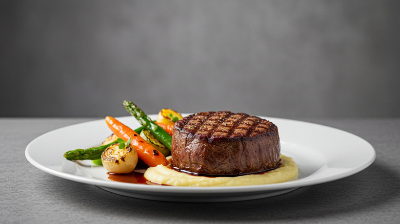 A grilled steak with mashed potatoes and vegetables on a white plate