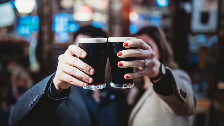 Two people clinking glasses of Guinness