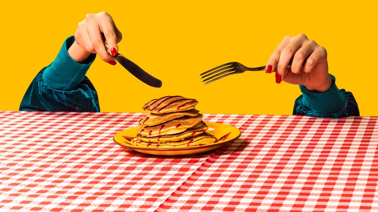 A person getting ready to eat a stack of pancakes