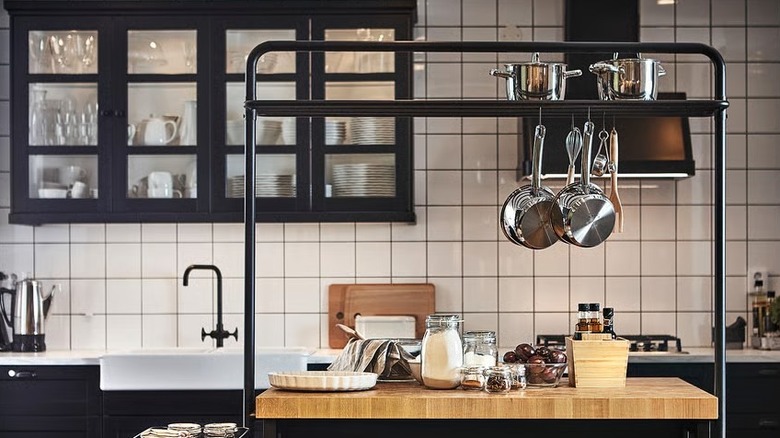 kitchen island with hanging rack with pots and pants hanging and stacked on it