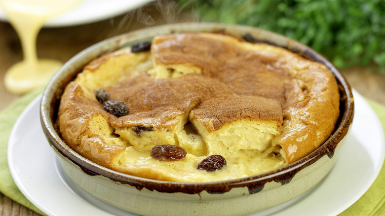 Raisin bread pudding in a baking pan resting on a white plate