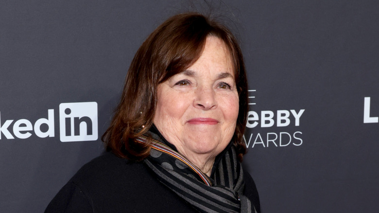 Ina Garten smiling in a black sweater and patterned scarf while attending a press event