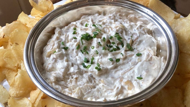 Ina Garten's pan-fried onion dip in a serving bowl surrounded by potato chips