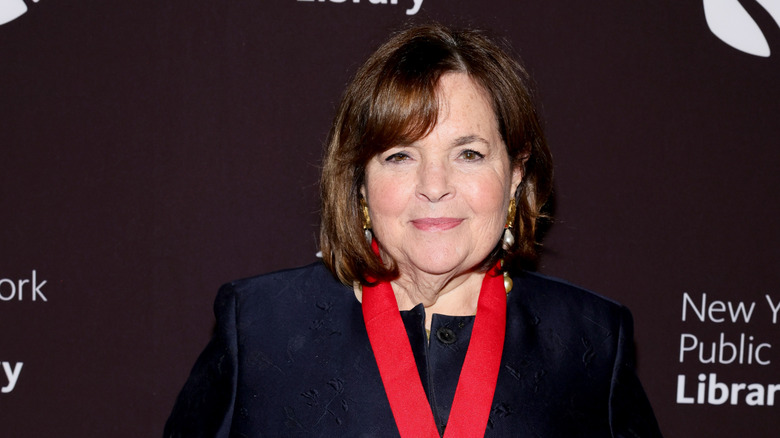 Close up of Ina Garten wearing a dark navy top and thick red ribbon around her neck.