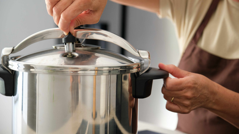 Woman adjusting the steam release on a pressure cooker