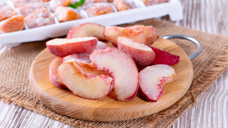 Frozen peach slices on wooden board