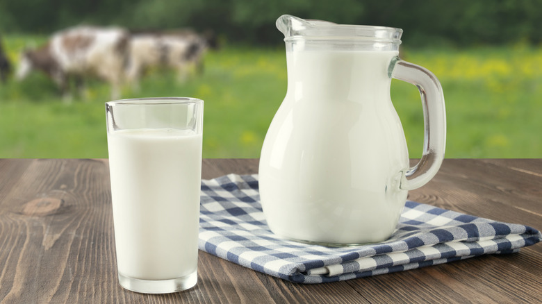 A glass and a pitcher of organic milk on a wooden table
