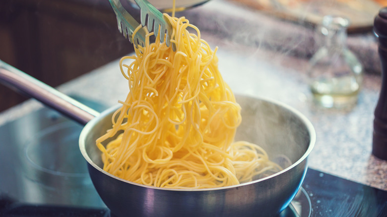 spaghetti in a pot being lifted by tongs