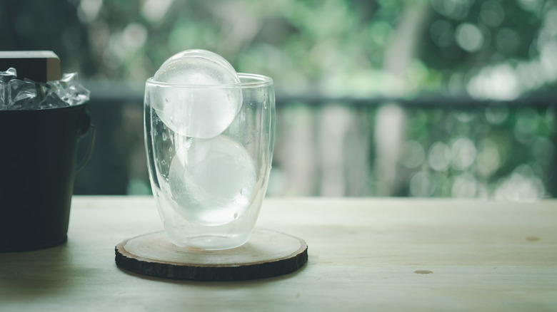 Two spherical ice molds in a glass cup
