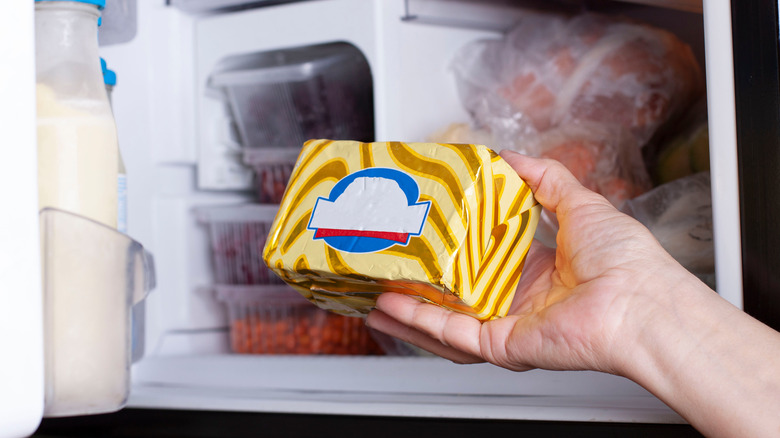 Person placing butter in fridge