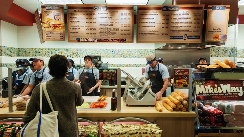 Employers behind the counter at a Jersey Mike's with a customer out front