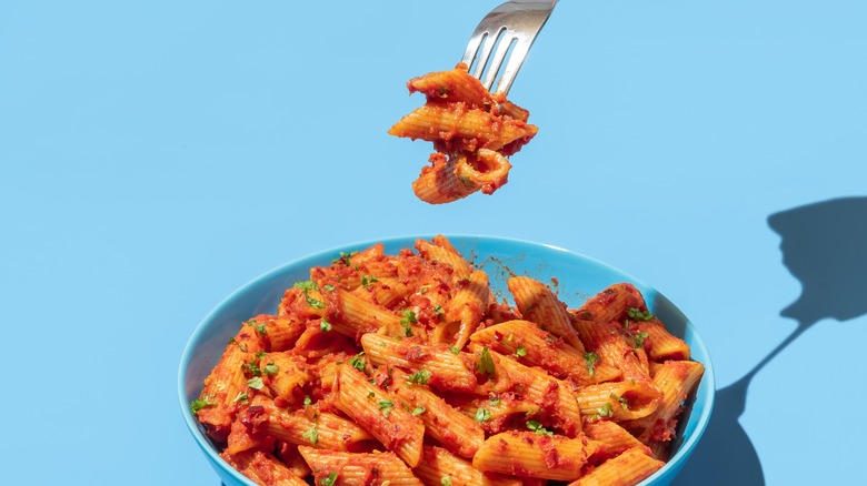Fork grabbing pasta in red sauce and blue bowl