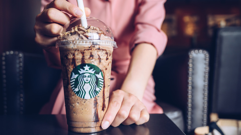 A woman holds a Starbucks Frappucino