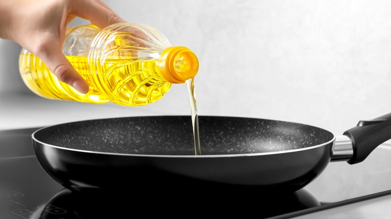 Person pouring oil into pan