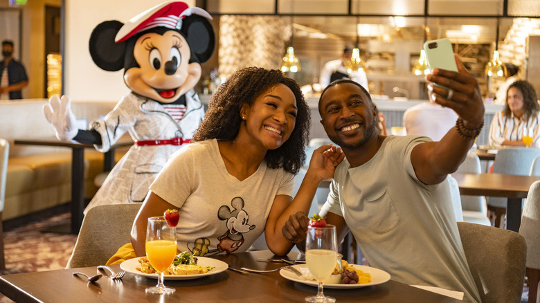 Disney guests eating breakfast taking selfie with Minnie