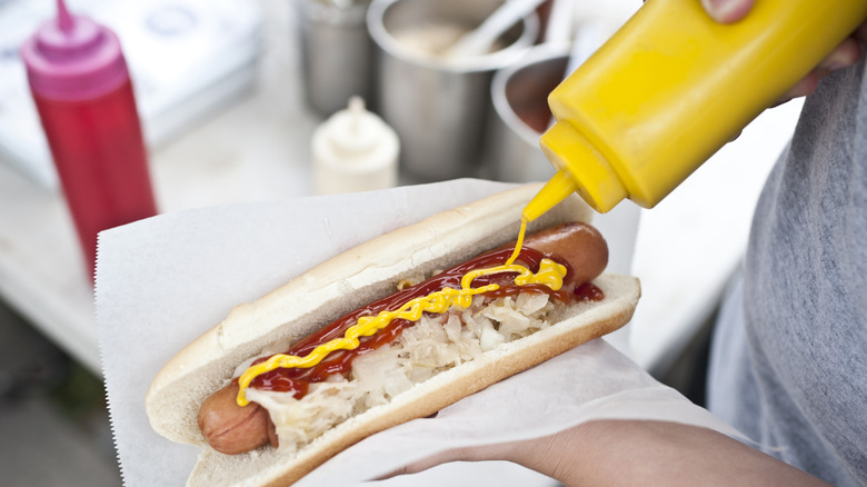 hot dog being squirted with mustard