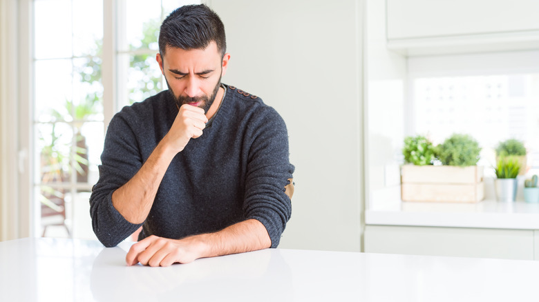 man coughing at table