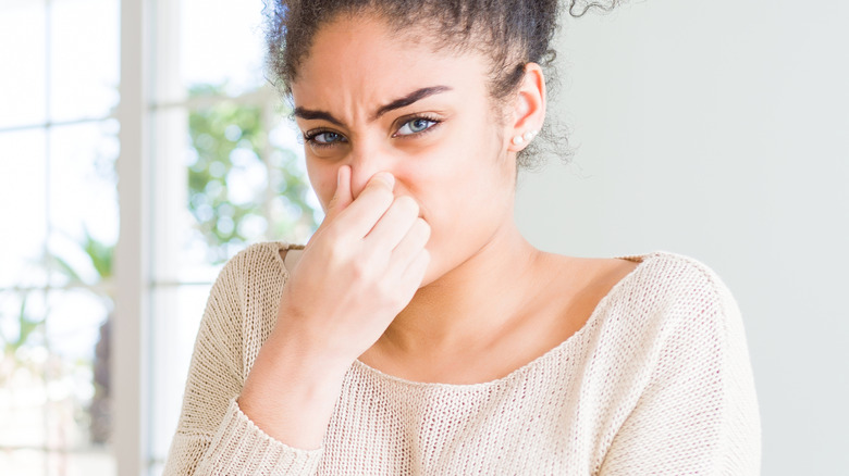 woman holding nose at table 