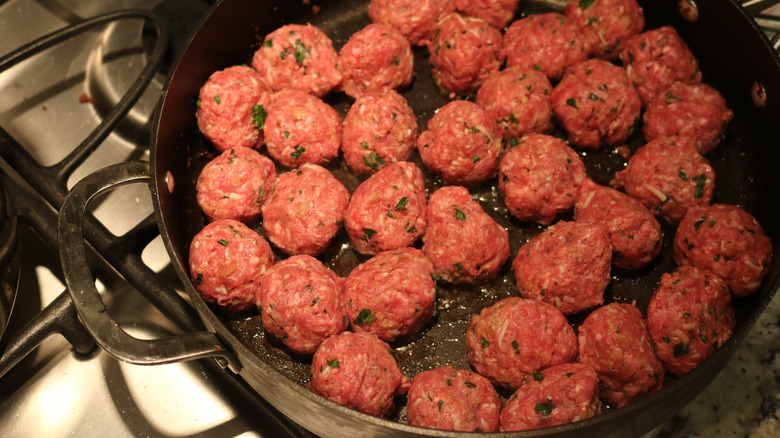 Raw meatballs searing in pan