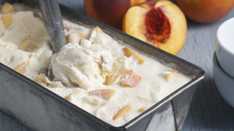 a scoop taken from homemade ice cream with peach chunks