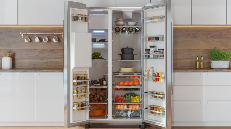 A large, open refrigerator in a modern kitchen filled with fresh food