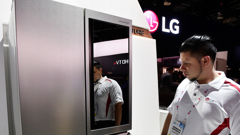 A man inspecting an LG refrigerator in a showroom