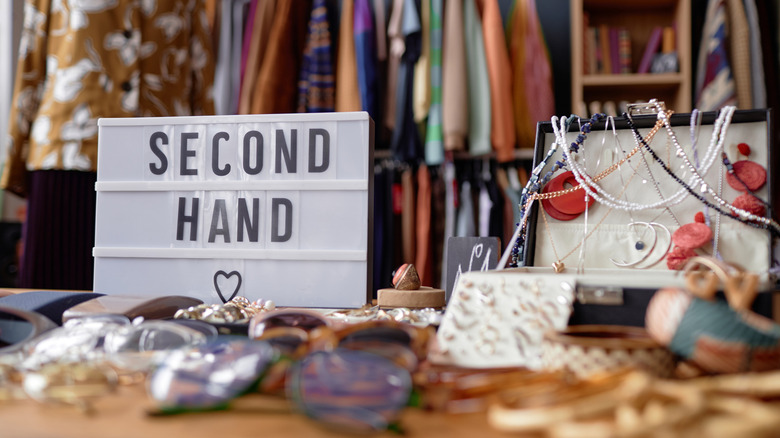 A table in a store with a "Second Hand" sign and various items.