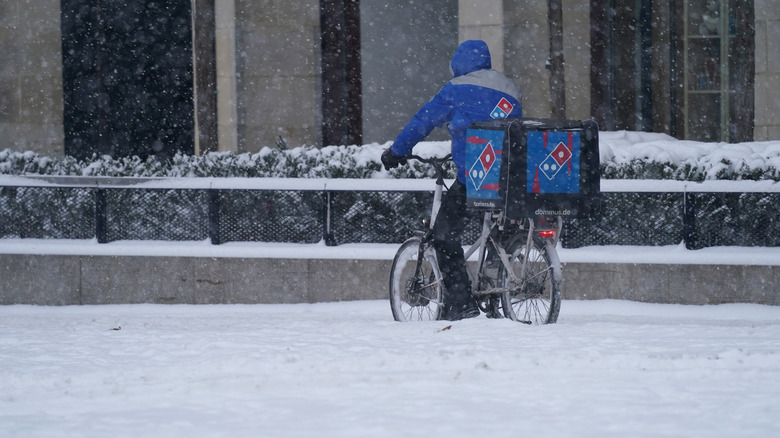 Domino's delivery driver on bike in snow 
