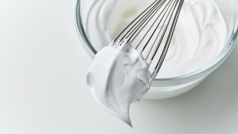 Bowl of whipped cream and a whisk with cream