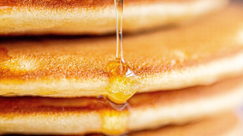 Closeup of a stack of pancakes drizzled in syrup