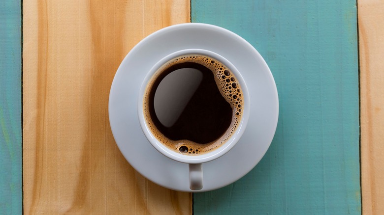 A cup of black coffee on a multicolored wooden table