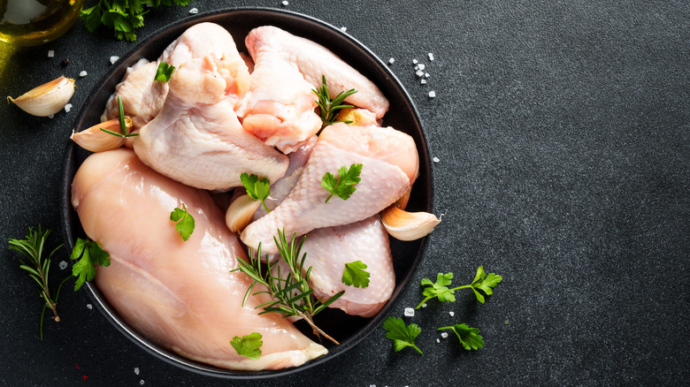 A top-down view of several pieces of raw chicken on a black plate