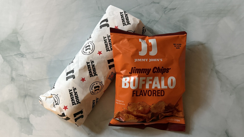 A wrapped Jimmy John's wrap and an orange bag of Buffalo chips